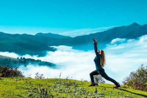 woman in black tank top and black leggings doing yoga on green grass field during daytime